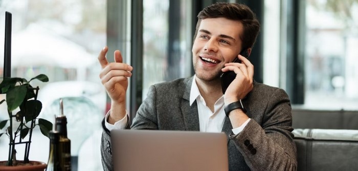 Man talking on phone while working on laptop.