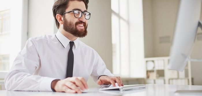 Man typing -n a computer smiling.